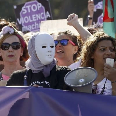 Joukko mielenosoitukseen osallistuneita naisia. Yhdellä on kasvoillaan naamio.