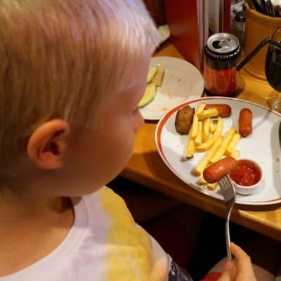Barn äter barnportion på restaurang.