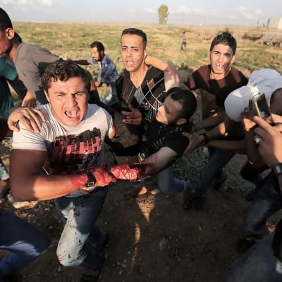 Palestiinalaisnuoret kantavat haavoittunut mielenosoittajaa turvaan Israelin tulitukselta Gazan ja Israelin välisellä rajalla 9. lokakuuta 2015.