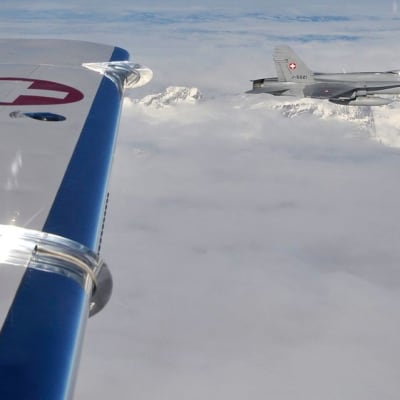 Sveitsiläinen F-18-hävittäjä harjoittelemassa tarkastuslentoa, toisen lentokoneen siipi näkyy kuvassa.
