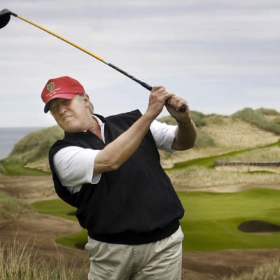 Donald Trump golfmaila kädessään,