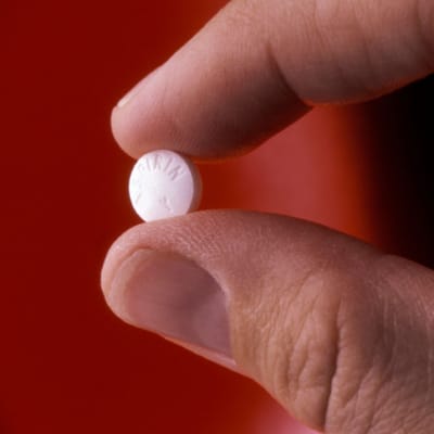 en tablett aspirin mellan tumme och pekfinger