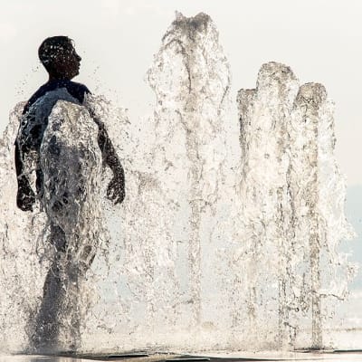 Mies viilentää itseään suihkulähteessä Evianin satamassa Ranskassa 16. heinäkuuta.