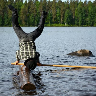 Hannu Kettunen seisoo käsillään tukin päällä.