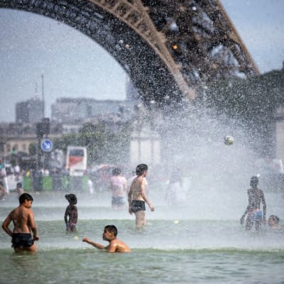 Ennätyshelteet koettelivat pariisilaisia kesäkuun lopussa. Turistit ja kaupunkilaiset vilvoittelevat Jardins du Trocadero-puistossa Eiffel-tornin juurella.