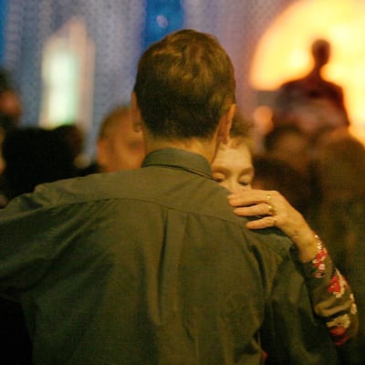 Mies ja nainen tanssivat, takana näkyy siluetissa orkesterin