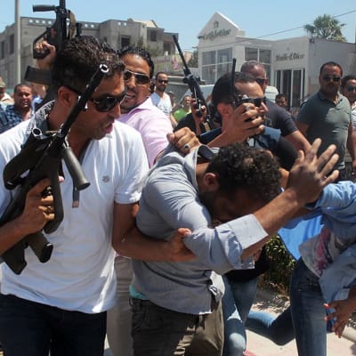 Tunisian turvallisuuspoliisi saattamassa tekijäksi epäiltyä miestä Soussessa perjantaina.