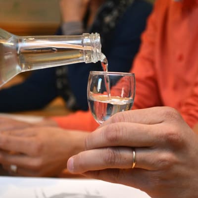 Pullosta kaadetaan kirkasta nestettä lasiin.  