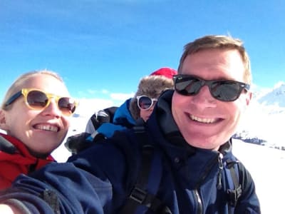 Tuomas Heikkilän perhe hiihtämässä Italian Alpeilla, taustalla sininen taivas ja vuoristomaisemaa.