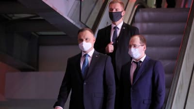 Den sittande presidenten Andrzej Duda (till vänster) och hans medhjälpare bar ansiktsmask då de lämnade en tv-studio efter en valdebatt på onsdagen. 