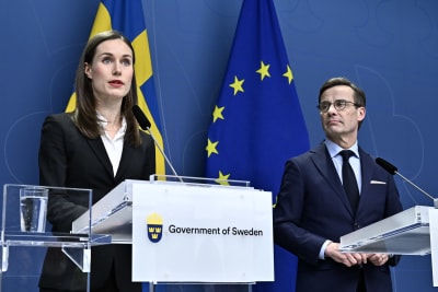 Finlands statsminister Sanna Marin och Sveriges statsminister Ulf Kristersson står vid talarstolar med Sveriges och EU-s flaggor i bakgrunden 