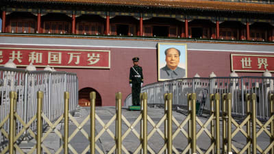 En polis står framför ett porträtt av Mao vid ingången till den förbjudna staden i Peking. 
