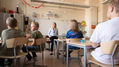 Fyra elever och en lärare sitter i ett klassrum.