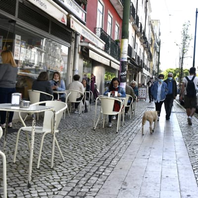 Folk sitter vid en uteservering i Lissabon.