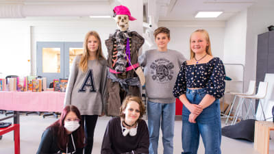 Fem tonåringar poserar med ett skelett