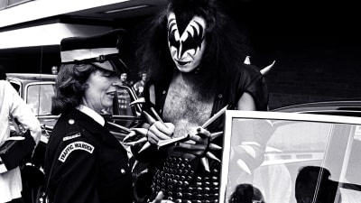 Kiss Gene Simmons i monstersmink ger autograf på brittisk kvinnlig polis.