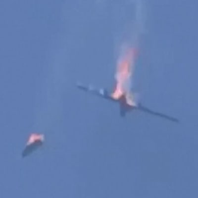 Brinnande vrakdelar faller mot marken mot bakgrunden av en blå himmel. Turkisk drönare sköts ned över Syrien.