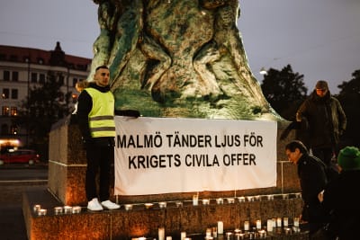 Aron Boklund Tendler och Bassem Nasr står framför ljus och ett plakat där det står Malmö tänder ljus för krigets civila offer.