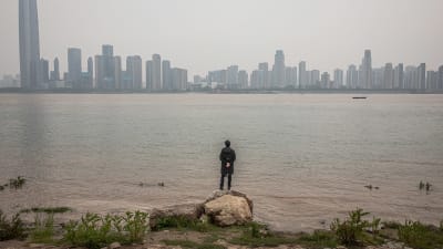 En man vid floden Yangtze tittar på staden Wuhan, Kina. 3.4.2020