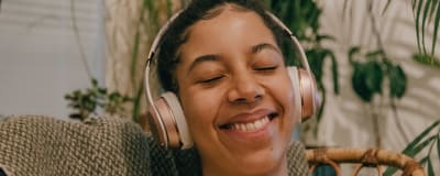 A girl listening to something on hear headphones with her eyes closed. She smiles.