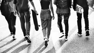 Svartvit bild på ett gäng tonåringar som promenerar bredvid varandra.