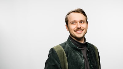 Nino Poppius står i en fotostudion och ler mot kameran. 