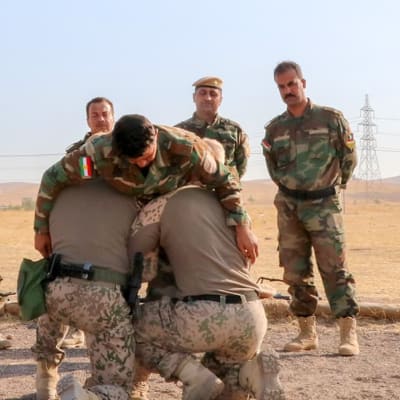 Finländare utbildar peshmergasoldater i Irak i november 2019. Soldaterna står i en halvcirkel och tittar på två soldater som lyfter upp en annan soldat.