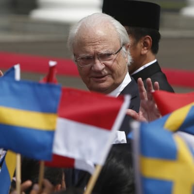 Kuningas vilkuttaa lapsille, jotka heiluttavat Ruotsin ja Indonesian lippuja.