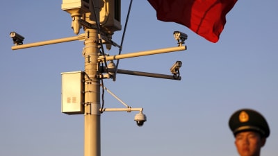 En kinesiska soldat står bredvid en rad övervakningskameror på Himmelska fridens torg i Peking