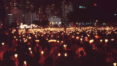 Personer står i en park och håller upp ljus.