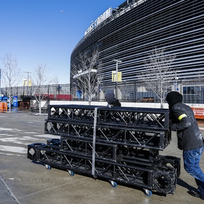 Kylmä säätä vastaan pukeutuneet työntekijät työntävät metallitelineitä kohti MetLife -stadionia New Jersey:ssä 29. tammikuuta.