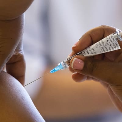 Lähikuva rokotteen pistämisestä olkavarteen.