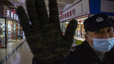 En säkerhetsvakt på marknaden i Wuhan sätter sin hand framför kamerans objektiv.