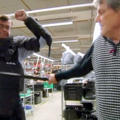 Silmälasipäinen mies on pukenunut suojavarusteita päälleenja saa patukasta iskuja