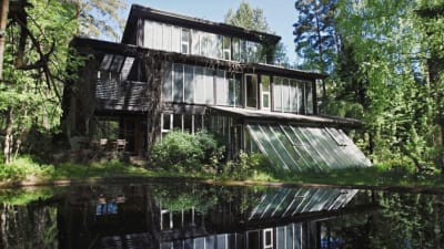 Bruno Erats året runt hus med många fönster speglas i vattnet