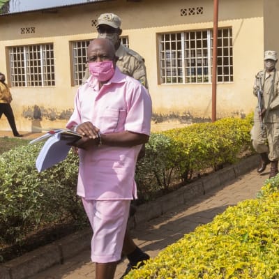 Kuvassa etualalla kävelee Paul Rusesabaguna vaaleanpunaisessa vangin asussa. Hänen takanaan kävelee kolme vartijaa. 