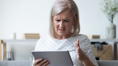 Medelålders kvinna titttar frustrearat på en pekdator