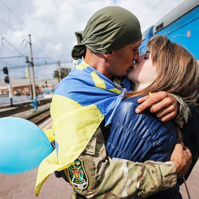 Rintamalta palannut ukrainan armeijan sotilas suutelee tyttöystäväänsä Kiovan asemalla.