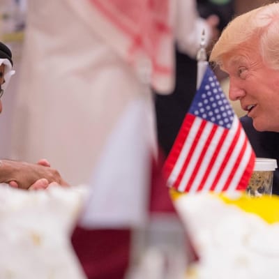 Abu Dhabin kruununprinssi ja Trump kättelevät. Etualalla pöydällä on pieni Yhdysvaltain lippu.