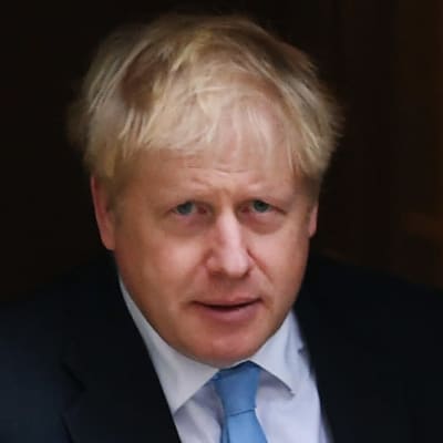 Premiärminister Boris Johnson i kostym och blå slips. Till höger en dörr.