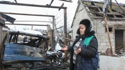 En kvinna i byn Novoluganskoje, i Donetsk, visar upp sitt skadade garage efter granatbeskjutning den 20 december. 