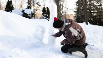 Aleksi Lehikoinen som skulpterar ett snöträd.