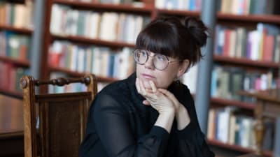 Anna Lindholm läser Anna Wiiks efterlämnade brev- och dagböcker sittande vid ett bord på Riksarkivet i Helsingfors.