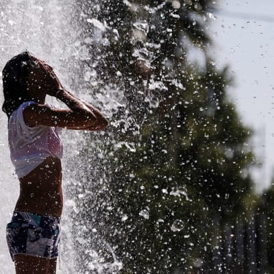 Nainen vilvoitteli suihkulähteessä Sevillassa 28. kesäkuuta 2015. 