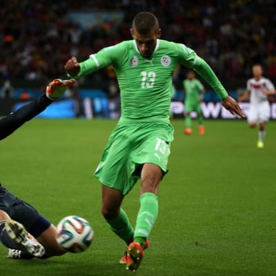 Saksan Manuel Neuer liukuu pallon Algerian Islam Slimanin jaloista.