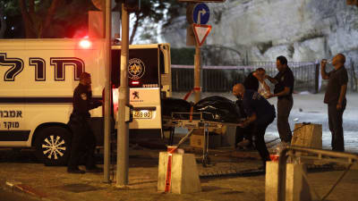 Räddningspersonal för bort kroppen av en av de tre palestinier som angrep poliser i Jerusalem