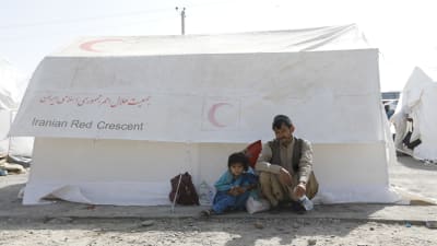 Två personer sitter vid ett tält på gränsen mellan Afghanistan och Iran.