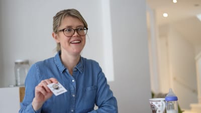 Kvinna sitter vid ett bord med ett kort i handen.