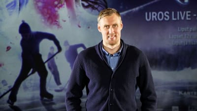 En leende man framför en bild på ishockeyspelare.