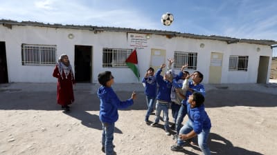 Skolbarn leker med en fotboll på Västbanken.